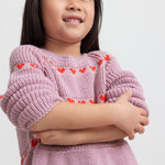 Pige iført lyserød strikkjole med røde hjerter