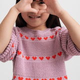 Pige iført lyserød strikkjole med røde hjerter