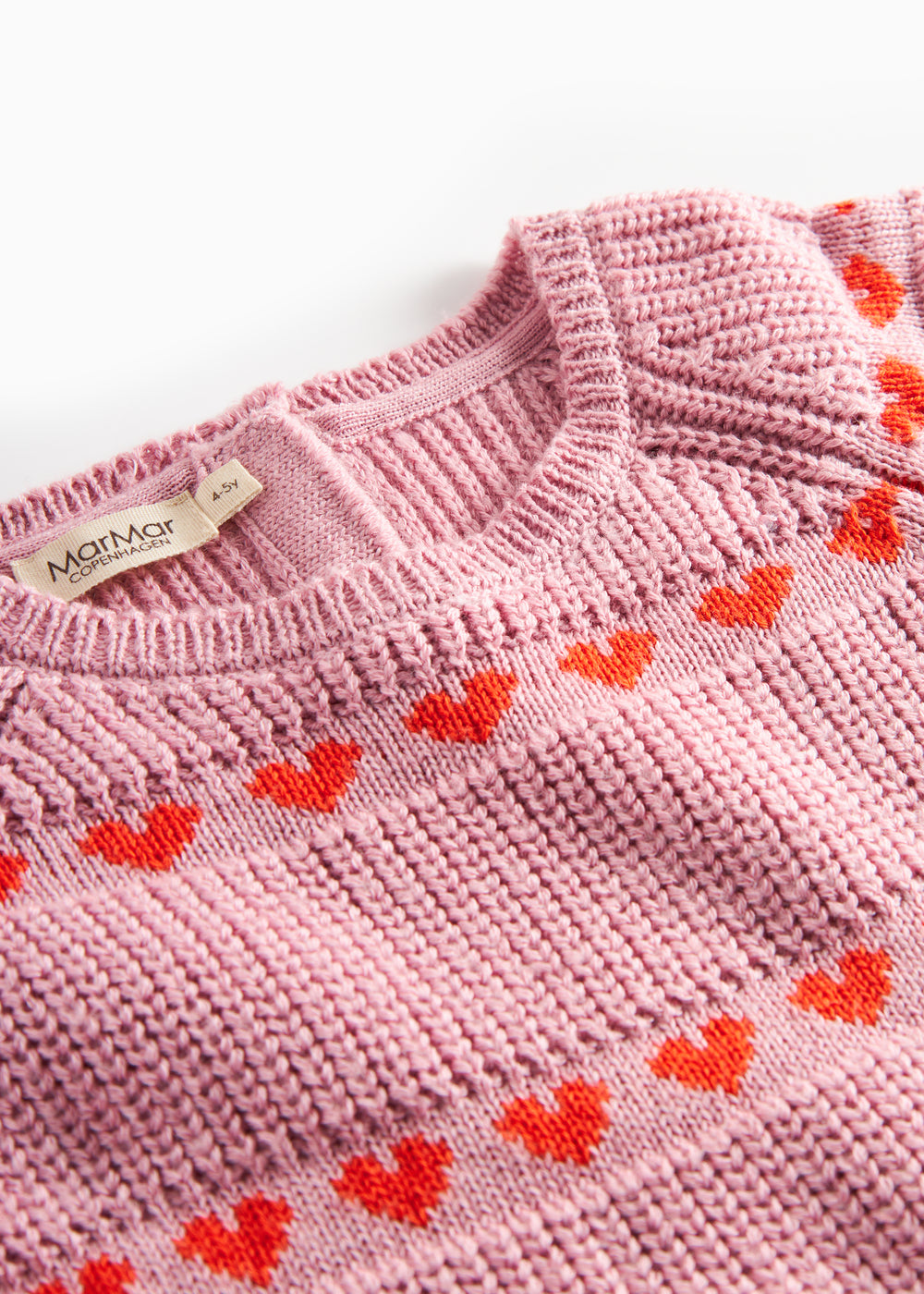 Nærbillede på lyserød strikkjole til børn med røde hjerter