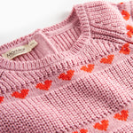 Nærbillede på lyserød strikkjole til børn med røde hjerter