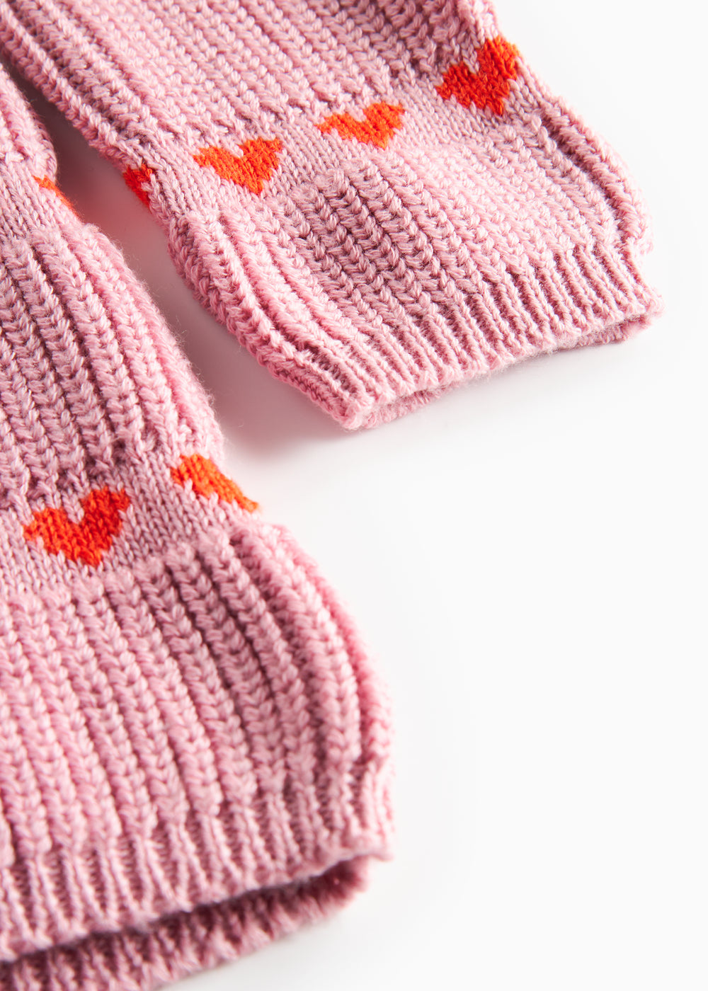 Nærbillede på lyserød strikkjole til børn med røde hjerter