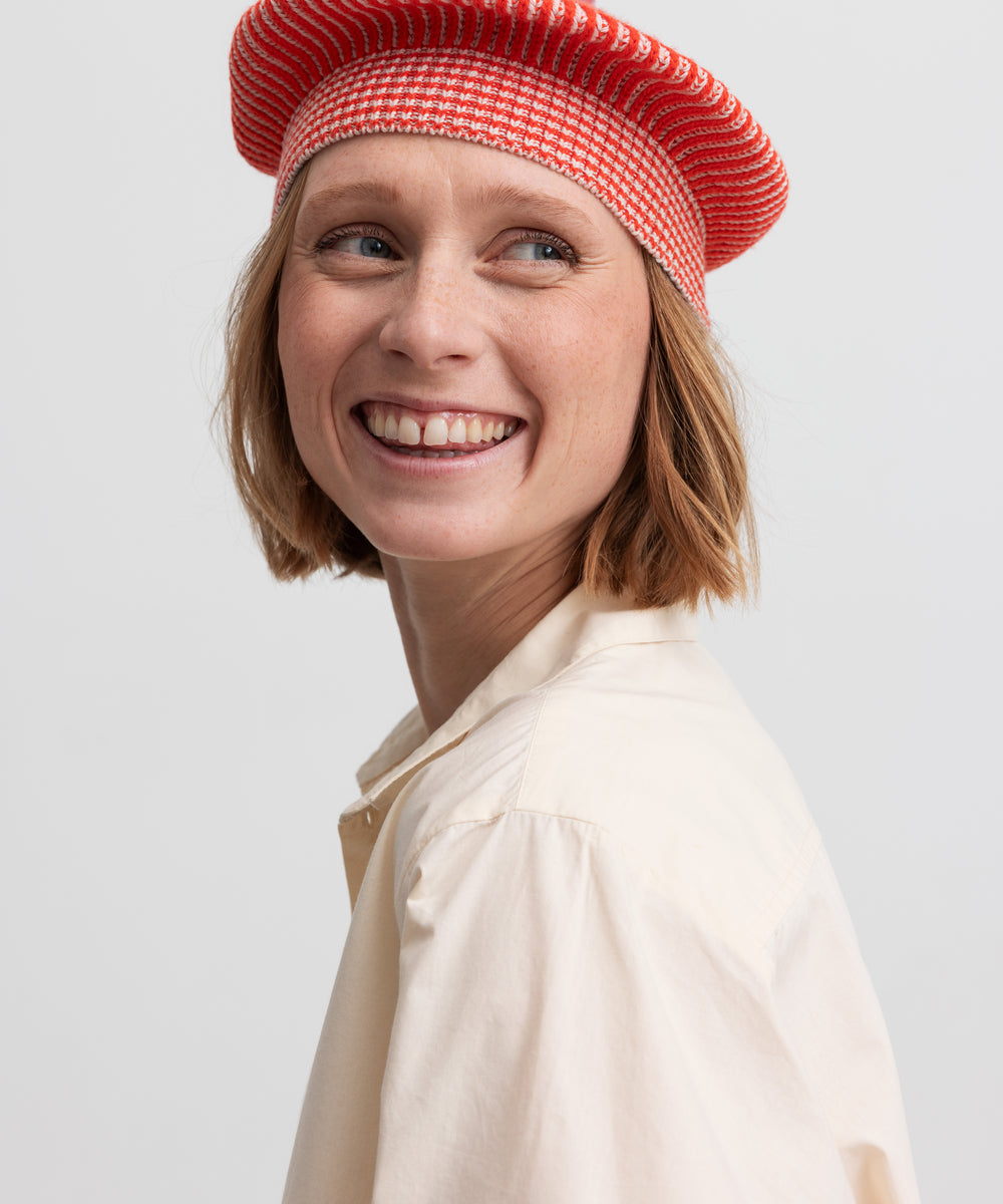 Kvinde iført rødstribet beret med lyserød kvast