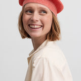 Kvinde iført rødstribet beret med lyserød kvast