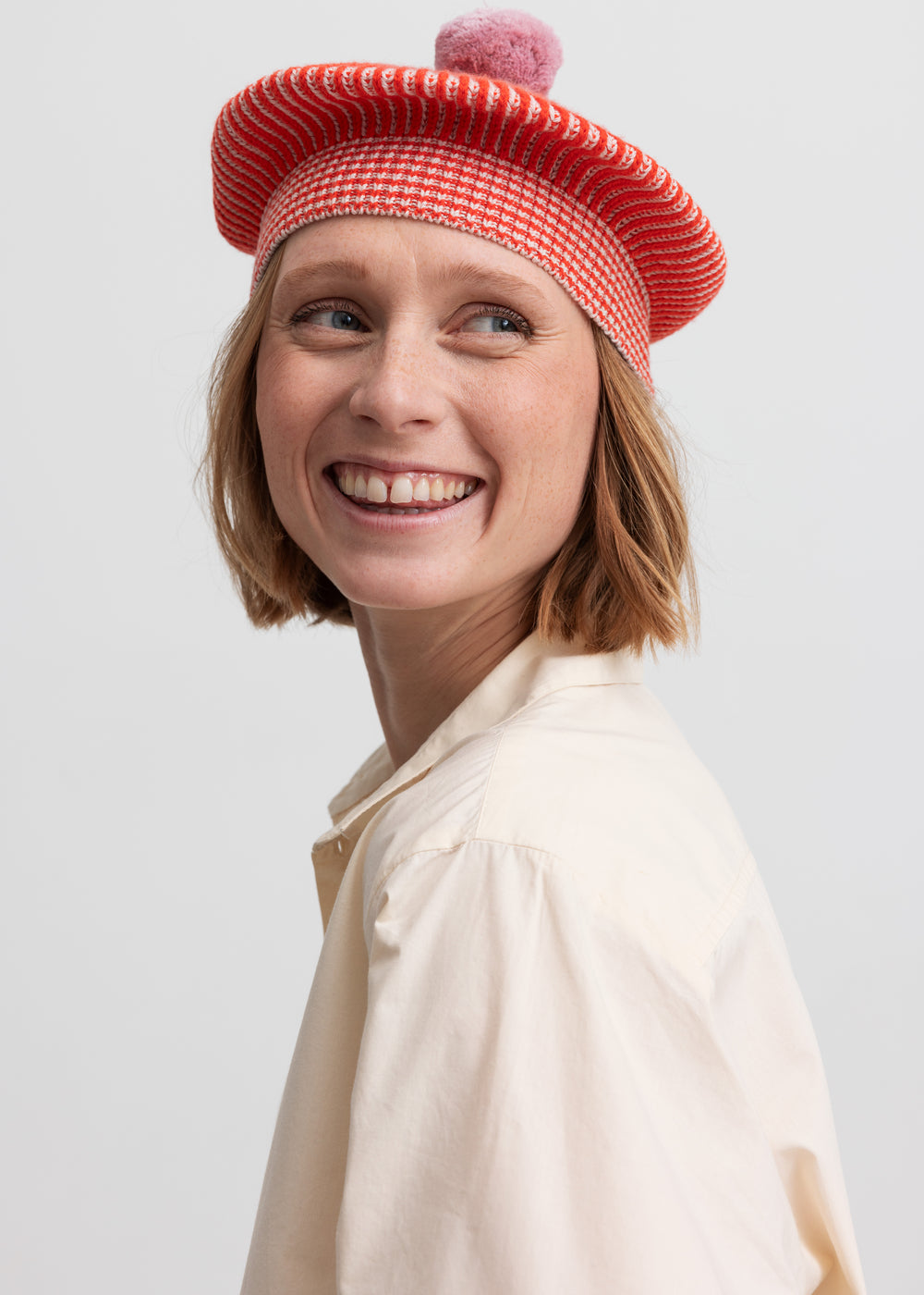 Nærbillede af kvinde med rød hue og cremefarvet bluse