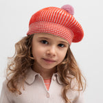 Pige iført rødstribet beret med lyserød kvast