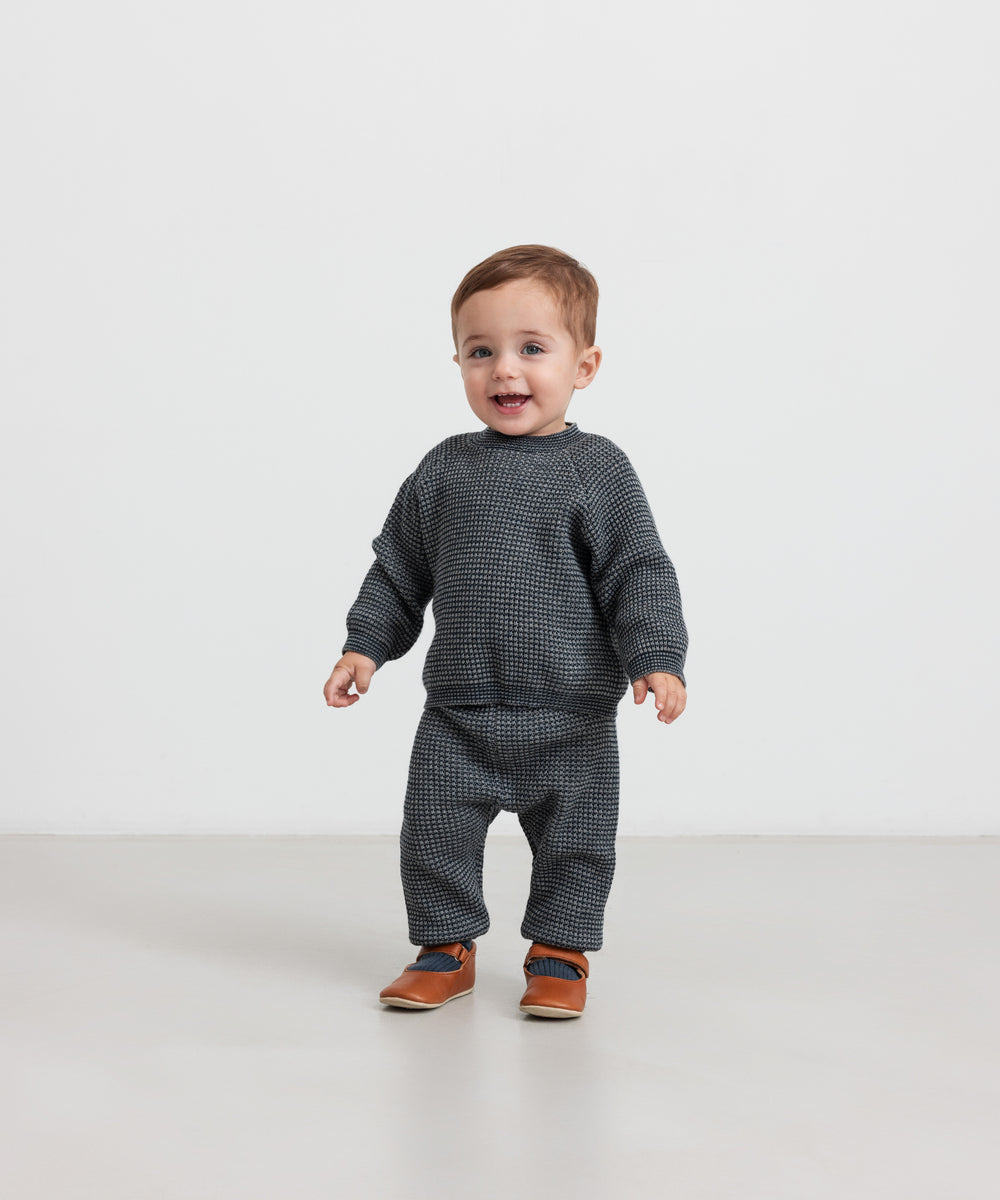 Baby iført mørkegrå strikket sweater og bukser