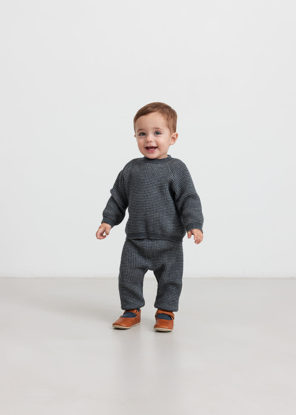 Baby iført mørkegrå strikket sweater og bukser
