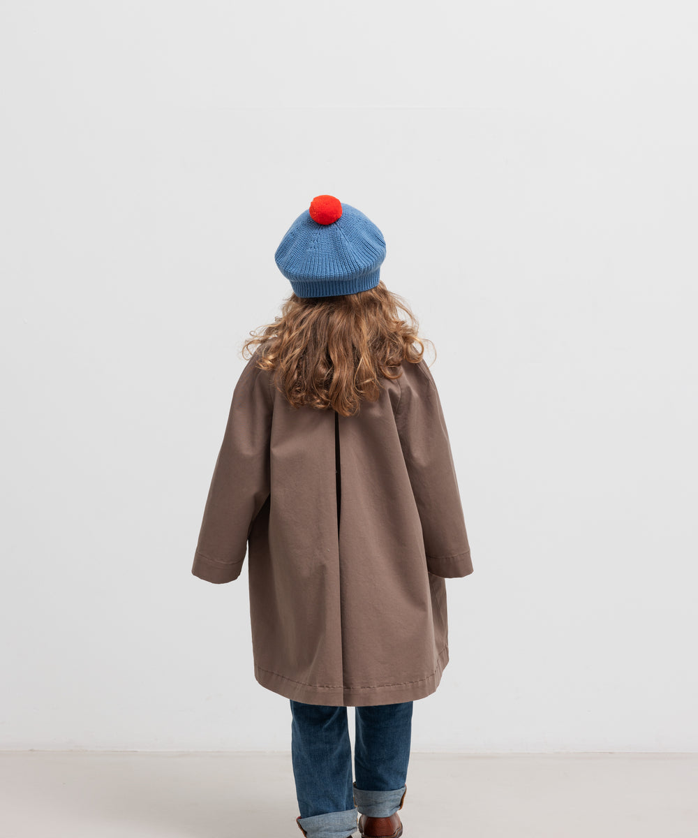 Pige bagfra med blå beret med rød kvast og brun frakke