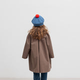 Pige bagfra med blå beret med rød kvast og brun frakke