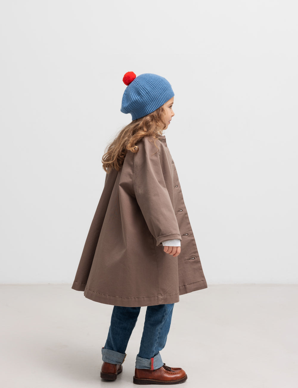 Børn med blå hue iført kaki chino frakke set bagfra