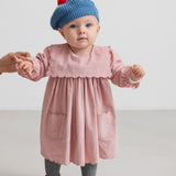 Baby i rosa kjole med blå strikket beret med rød kvast