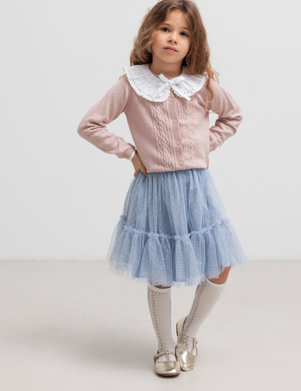 Child wearing blue layered tulle skirt and blouse with ruffled collar