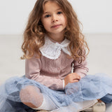 Børn sidder med lyserød strikcardigan og blød blå nederdel