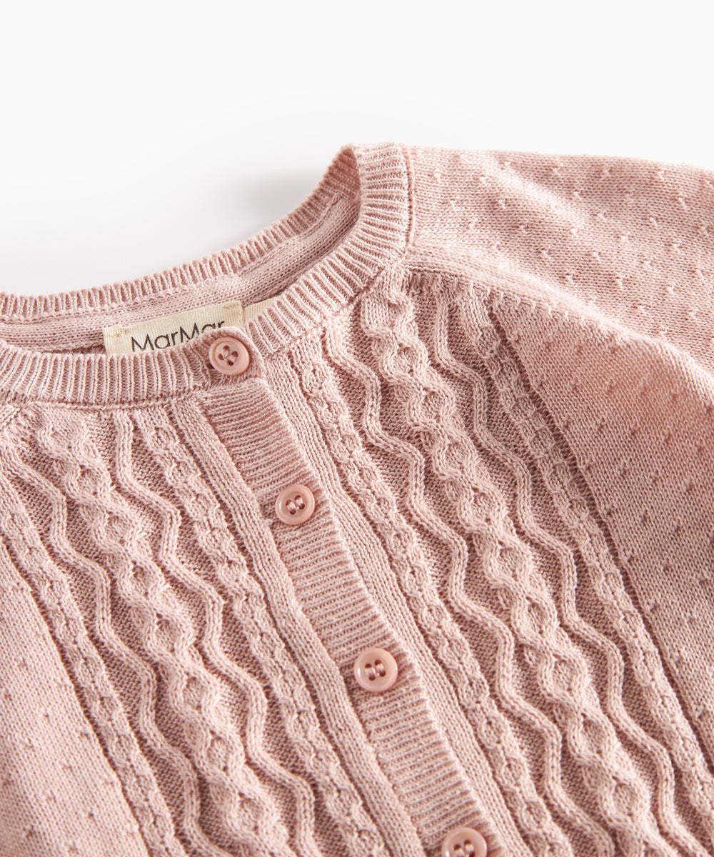 Nærbillede af forstykke på lyserød strikcardigan med mønsterstrik og knapper