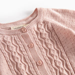 Nærbillede af forstykke på lyserød strikcardigan med mønsterstrik og knapper