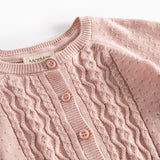 Nærbillede af forstykke på lyserød strikcardigan med mønsterstrik og knapper