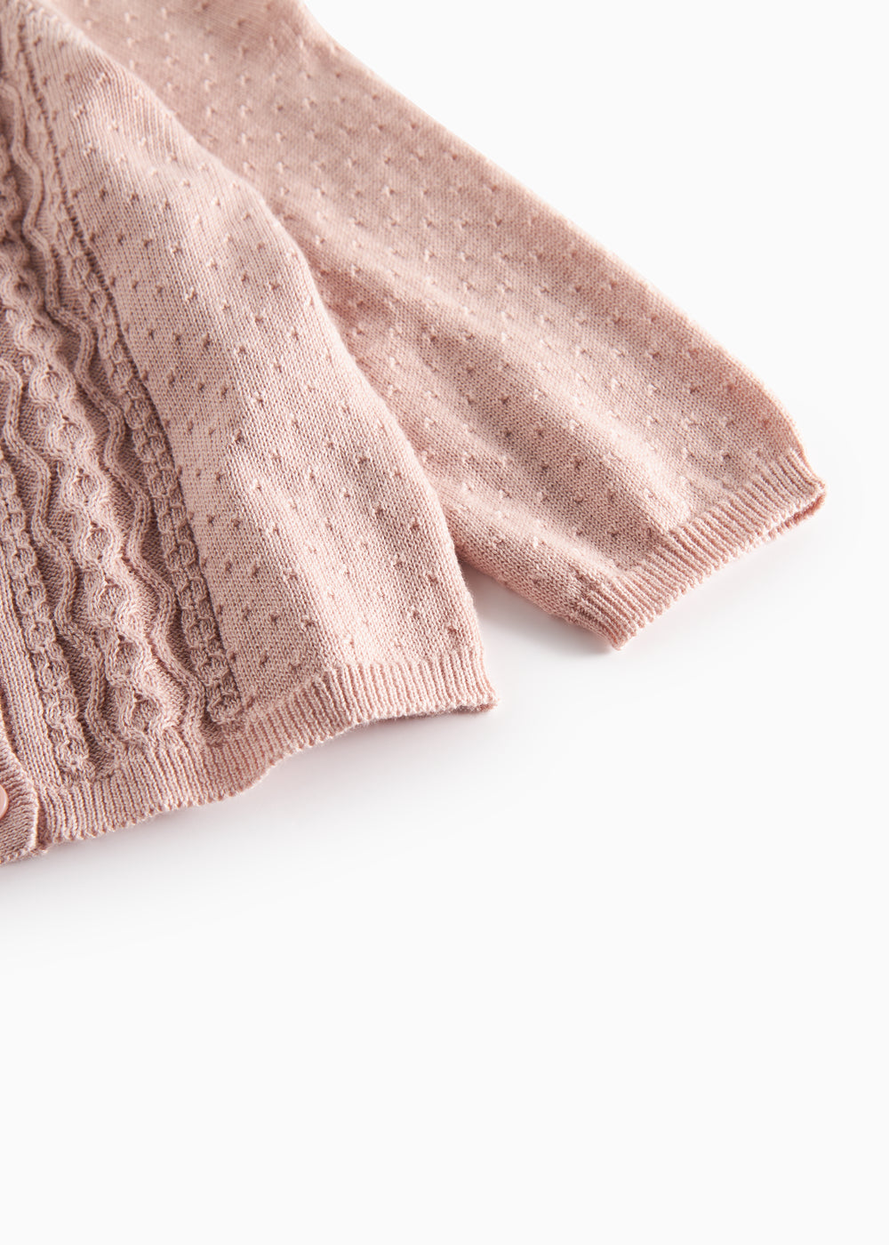Nærbillede af ærme på lyserød strikcardigan med mønsterstrik