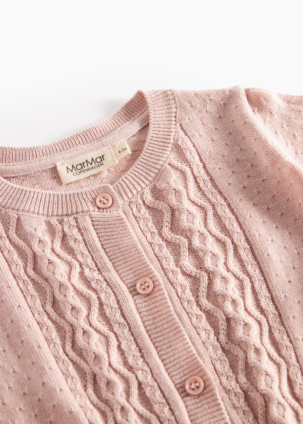 Nærbillede af forstykke på lyserød strikcardigan med mønsterstrik og knapper