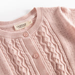 Nærbillede af forstykke på lyserød strikcardigan med mønsterstrik og knapper