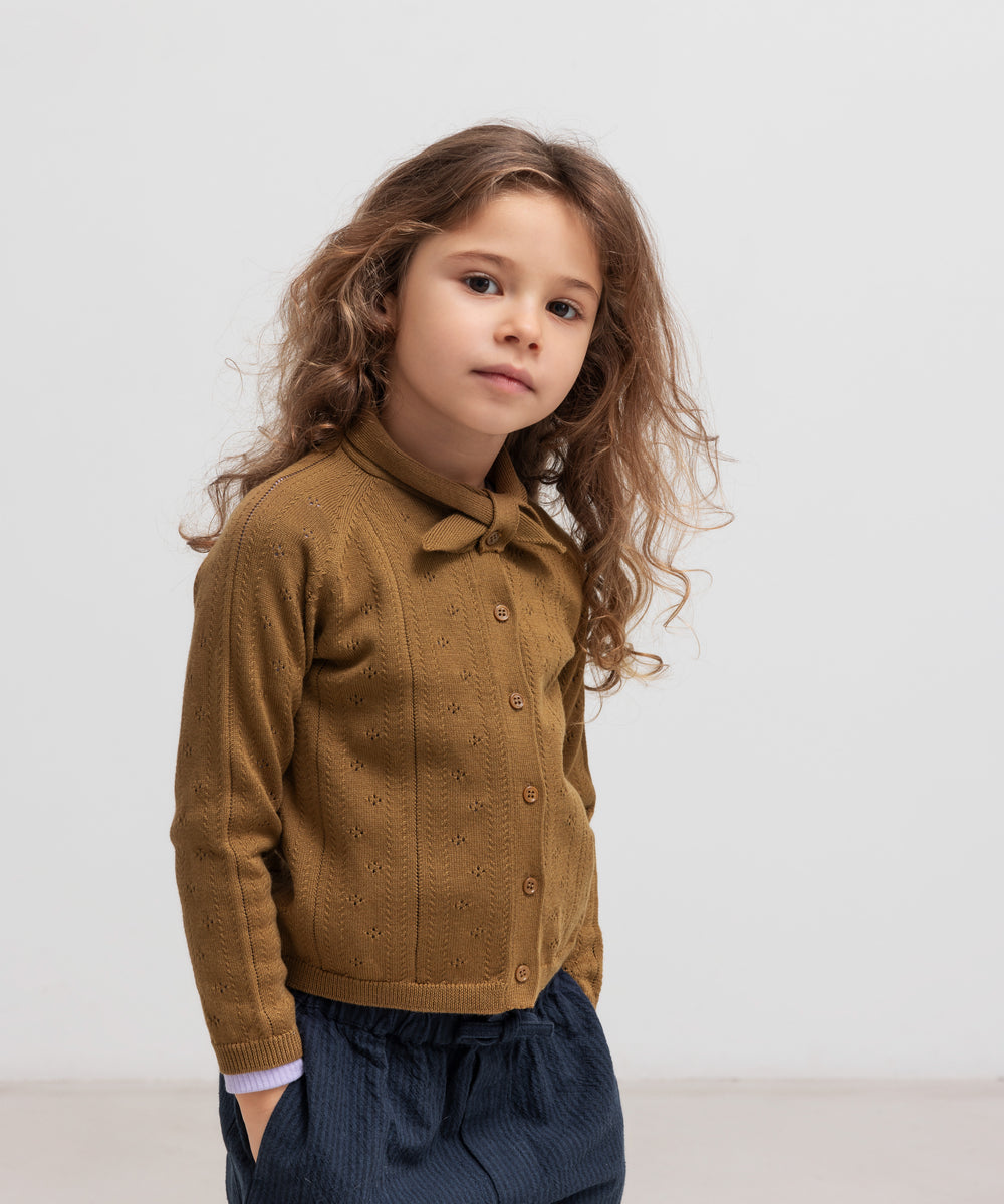 Børn iført mørkeblå bukser og brun strik cardigan