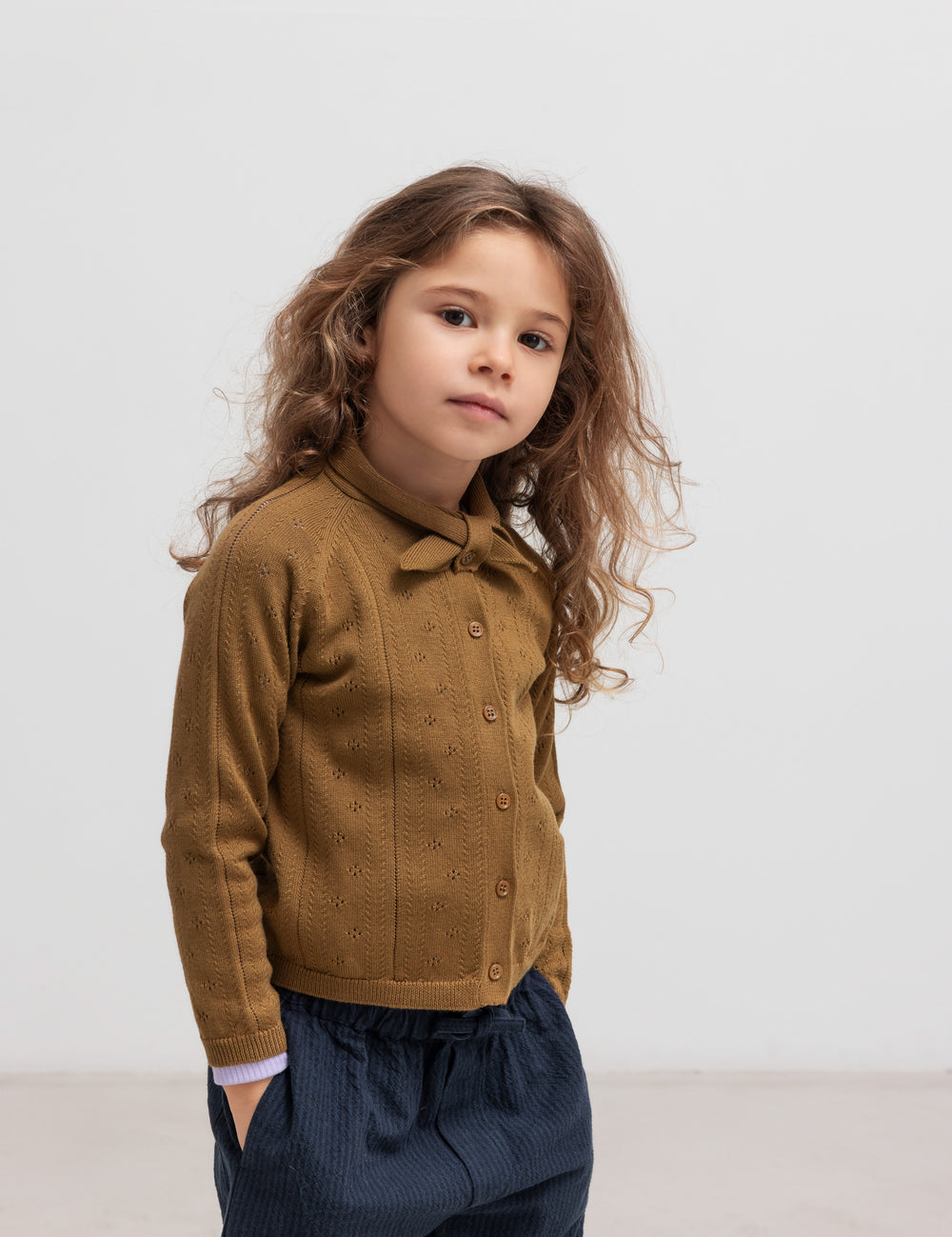 Børn iført mørkeblå bukser og brun strik cardigan