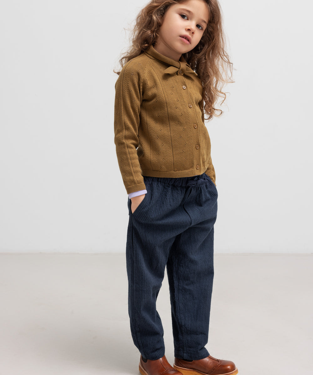 Børn iført mørkeblå bukser og brun strik cardigan