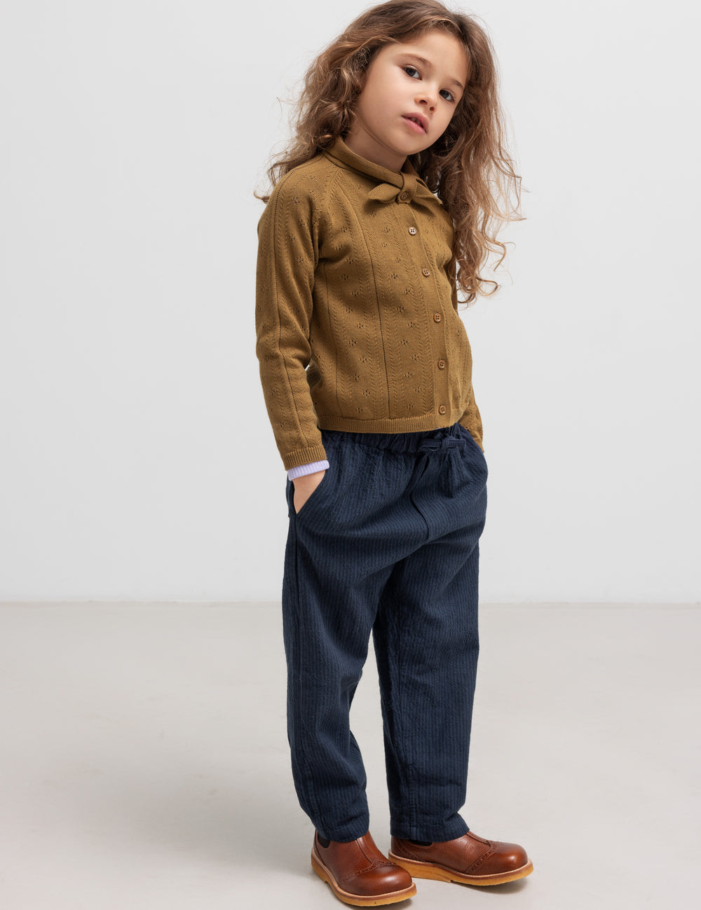 Børn iført mørkeblå bukser og brun strik cardigan