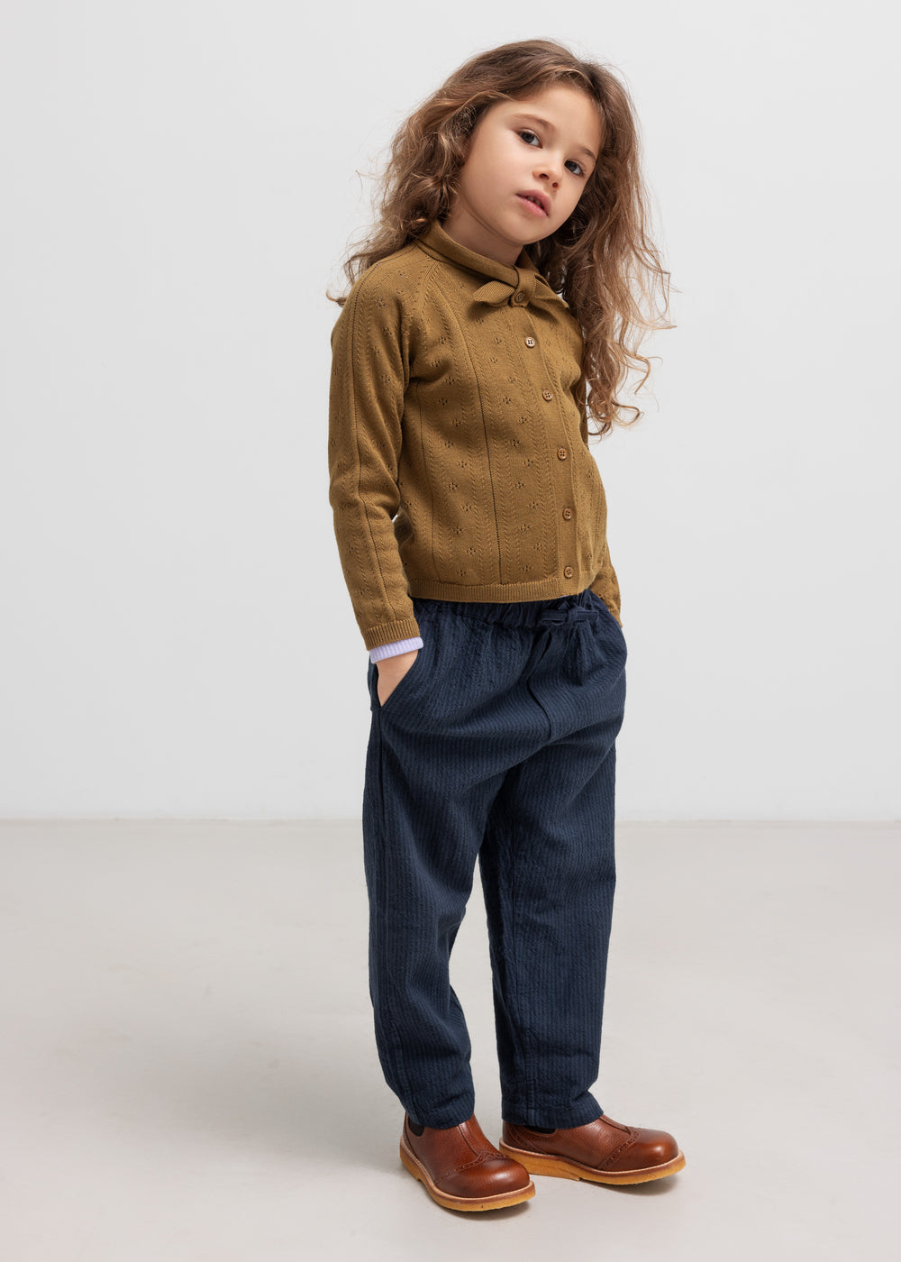 Børn iført mørkeblå bukser og brun strik cardigan