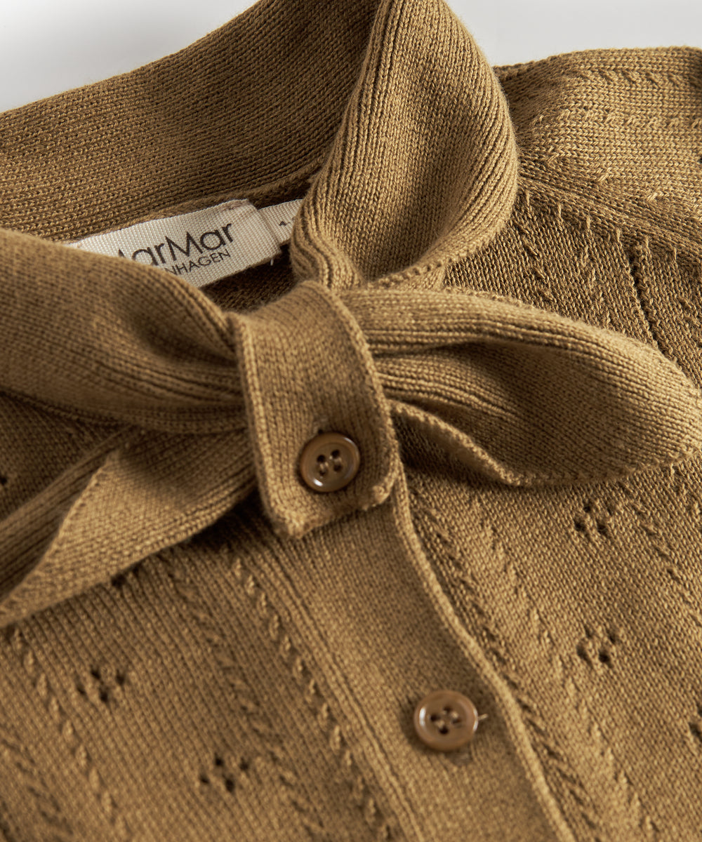 Nærbillede af sløjfe og knaplukning på cardigan