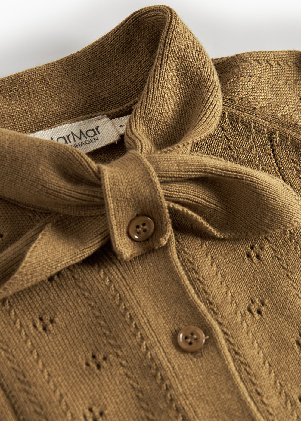 Nærbillede af sløjfe og knaplukning på cardigan