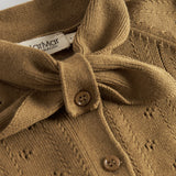 Nærbillede af sløjfe og knaplukning på cardigan