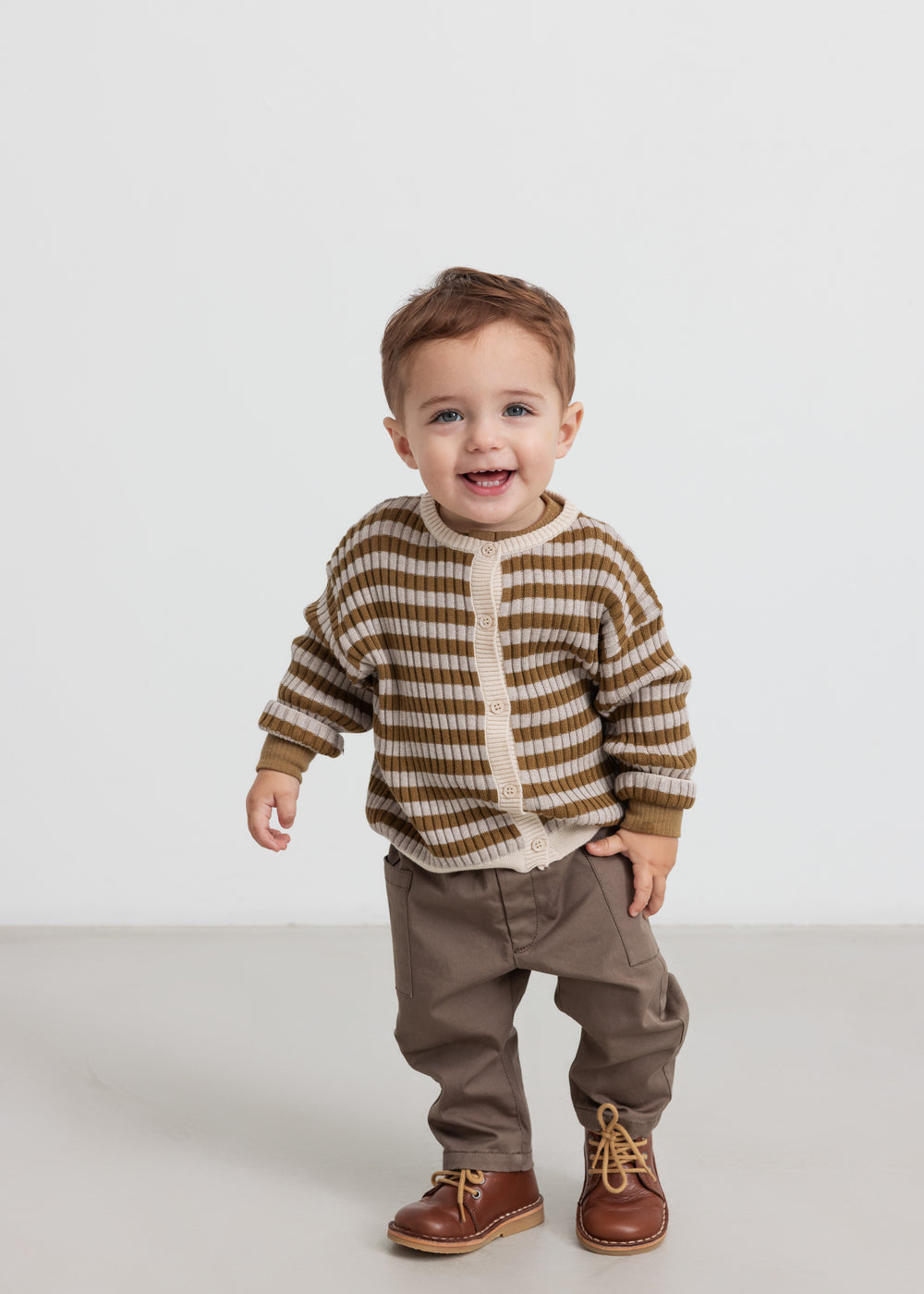 Børn iført stribet strikcardigan med knapper og brune bukser