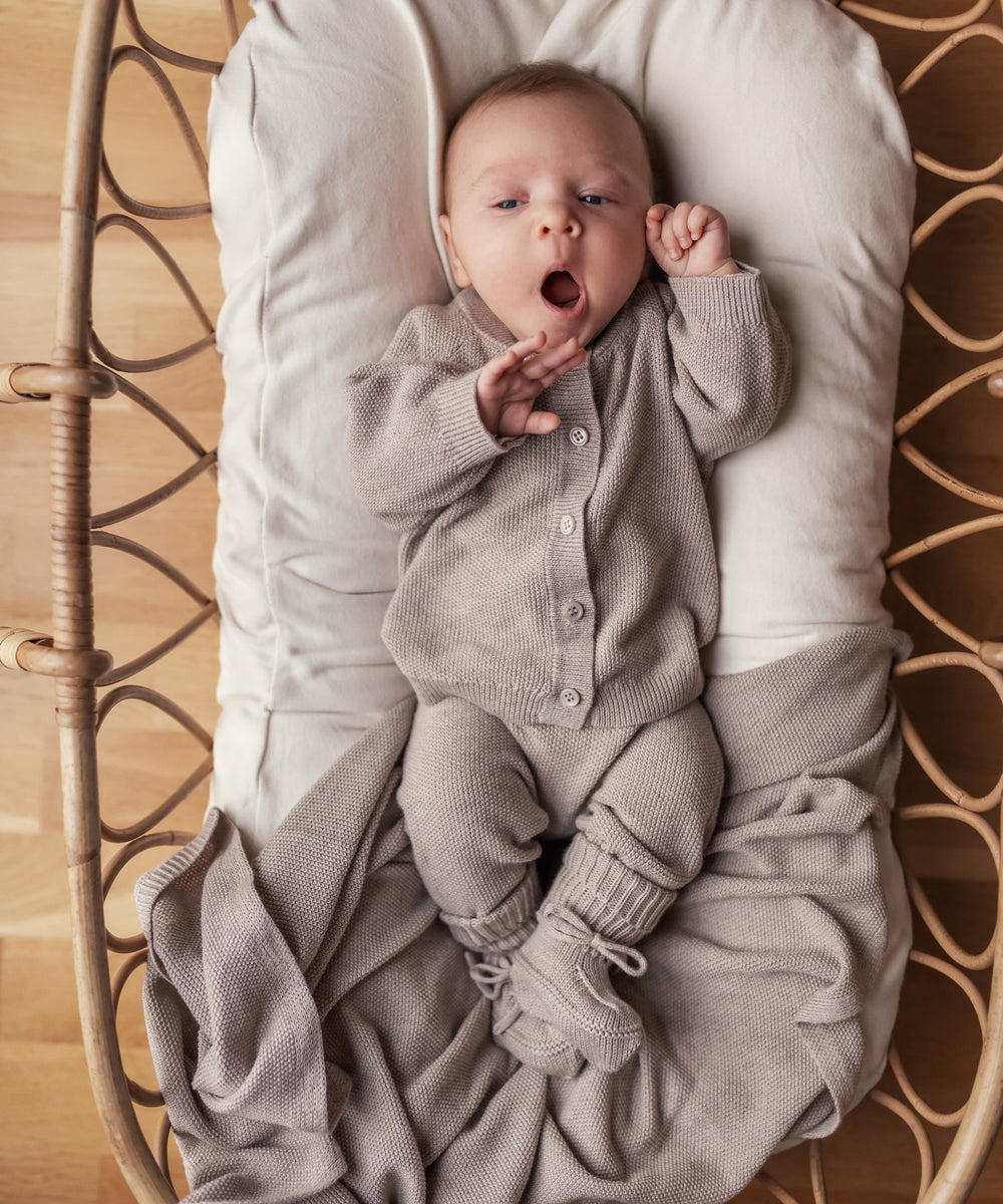 Baby iført beige strik babytøj