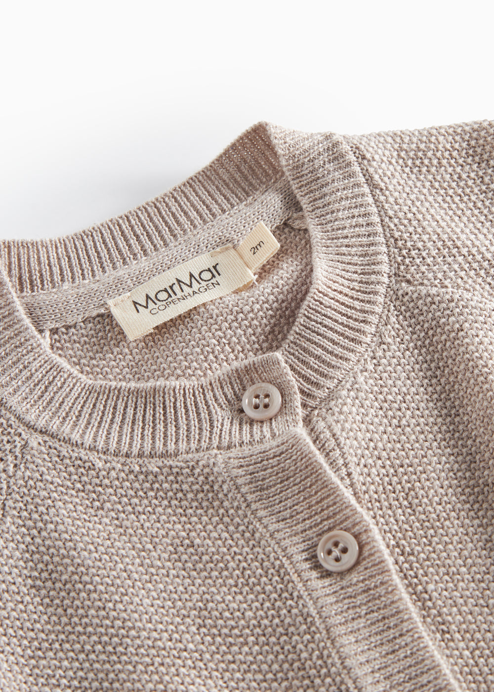 Nærbillede af knapper og ribkant på beige/grå strikket babycardigan