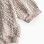 Nærbillede af ribkant ved ærme på beige/grå strikket babycardigan