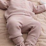 Nærbillede af ben i lyserøde strikkede babybukser med ribkanter og sløjfer