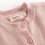 Nærbillede af knapper og halskant på lyserød strikket babycardigan