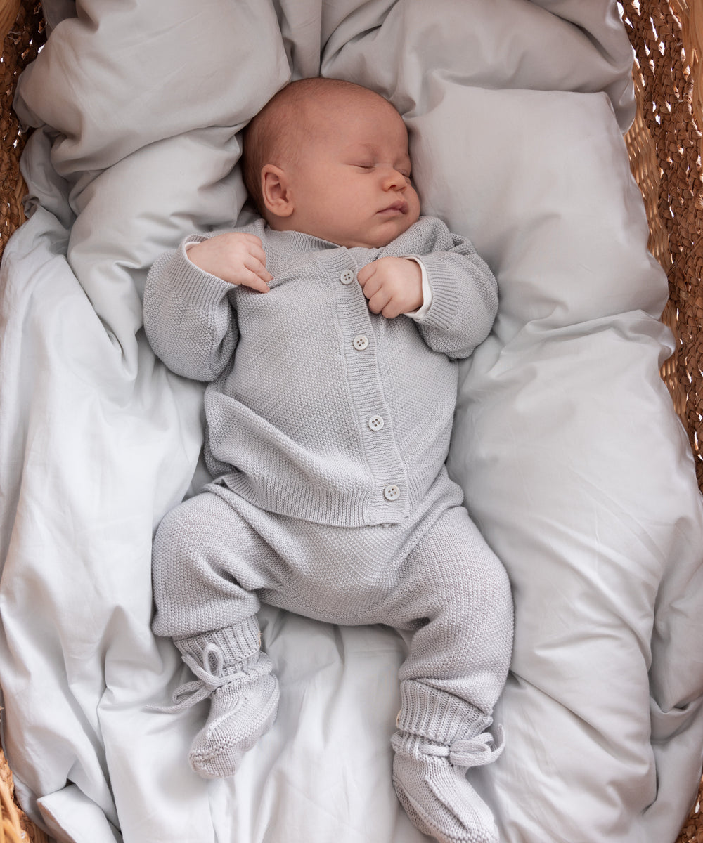 Baby sovende i blødt, gråt strikket babyoutfit
