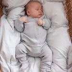 Baby sovende i blødt, gråt strikket babyoutfit