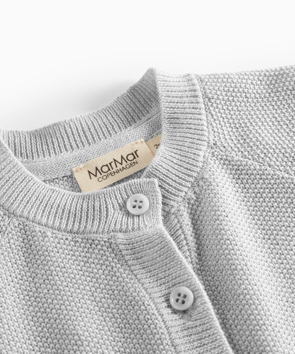 Nærbillede af knapper og halskant på lys grå strikket babytrøje
