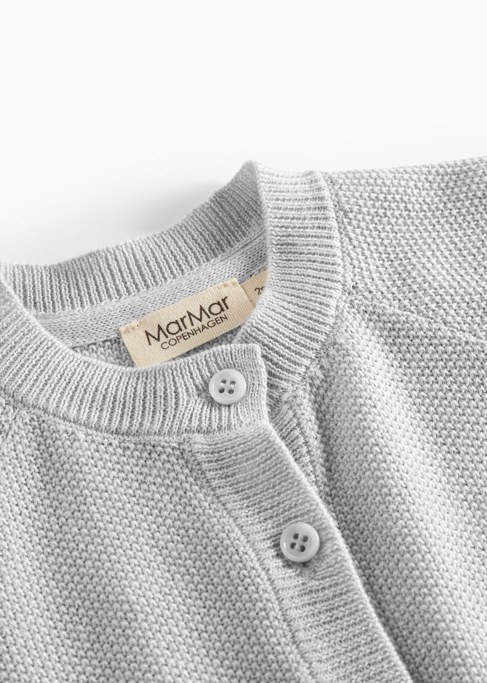 Nærbillede af knapper og halskant på lys grå strikket babytrøje