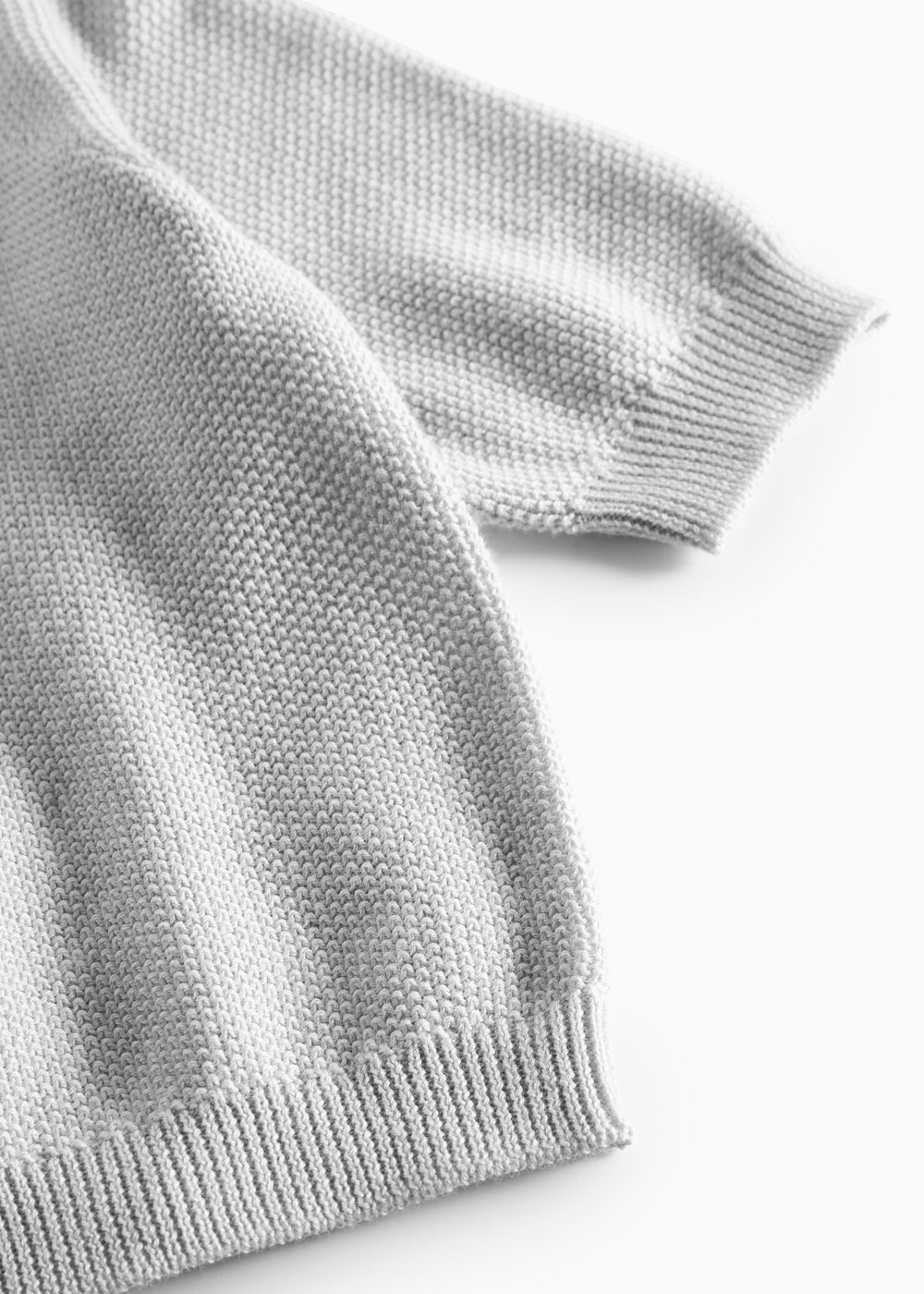 Nærbillede af ribkant ved ærme på lys grå strikket babytrøje