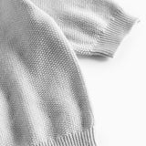 Nærbillede af ribkant ved ærme på lys grå strikket babytrøje