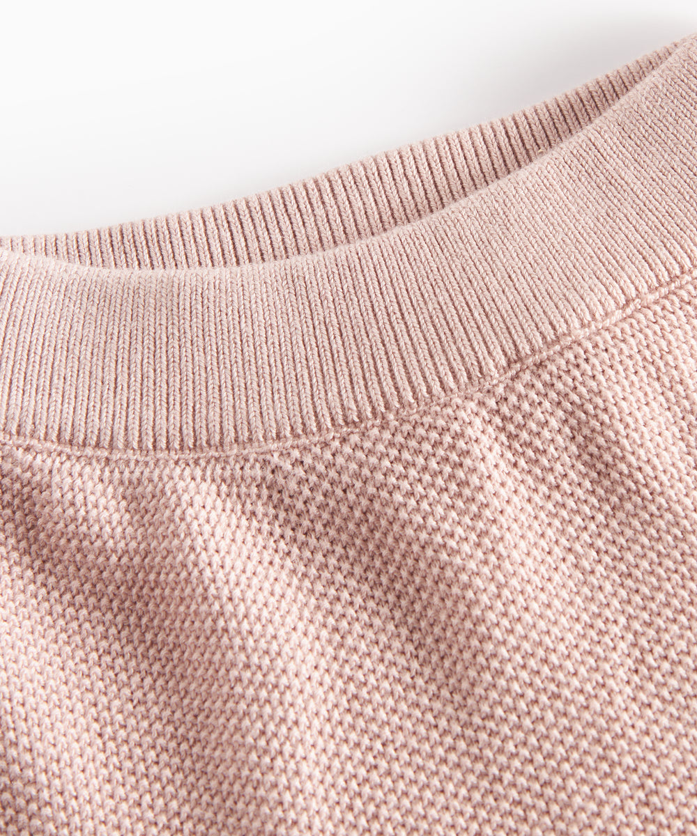Detalje af halsudskæring på lyserød strikket babytrøje