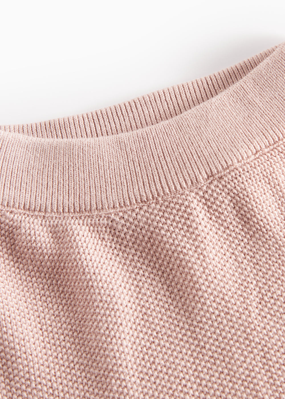 Detalje af halsudskæring på lyserød strikket babytrøje