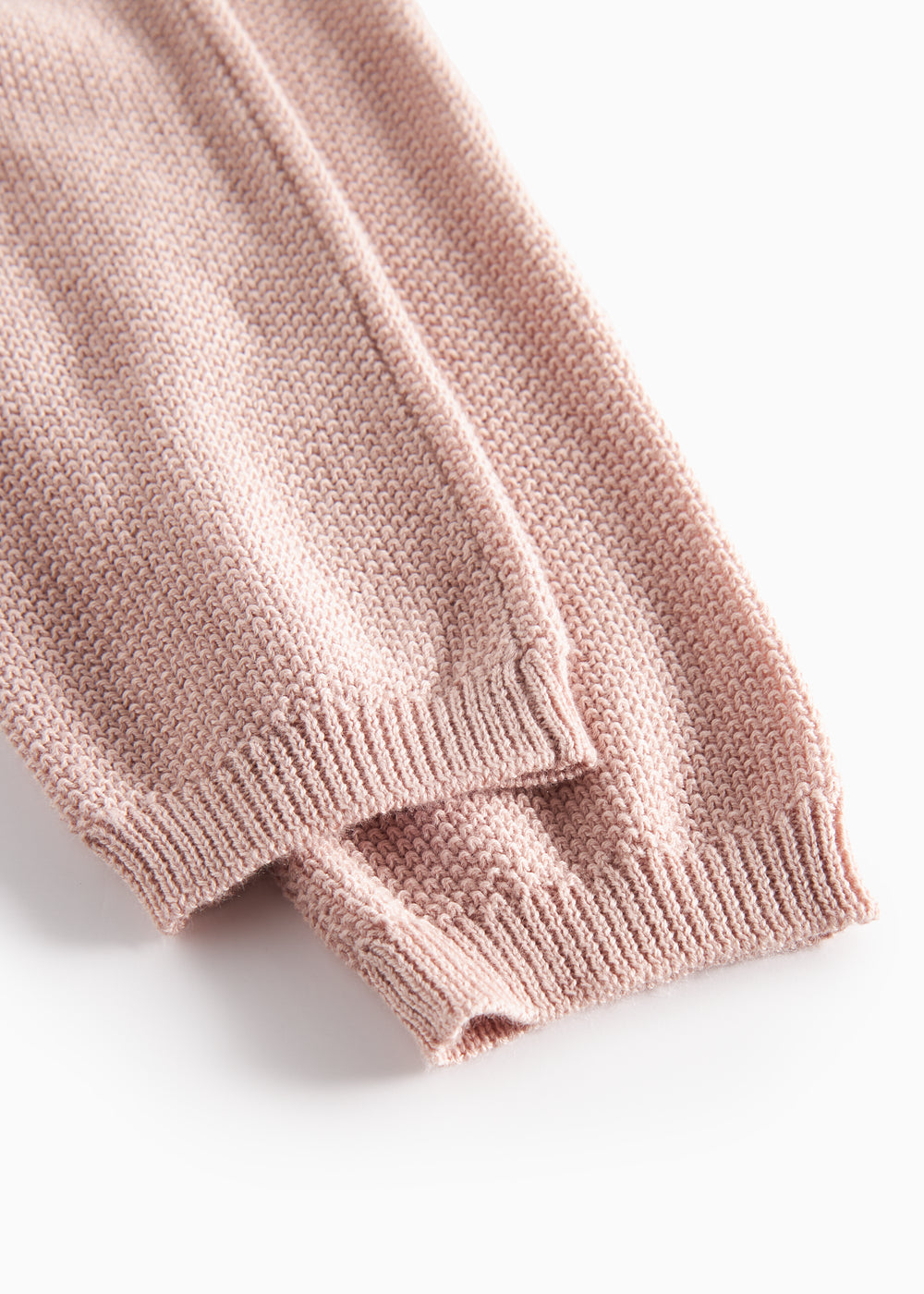 Nærbillede af ribkant på ærme af lyserød strikket babytrøje