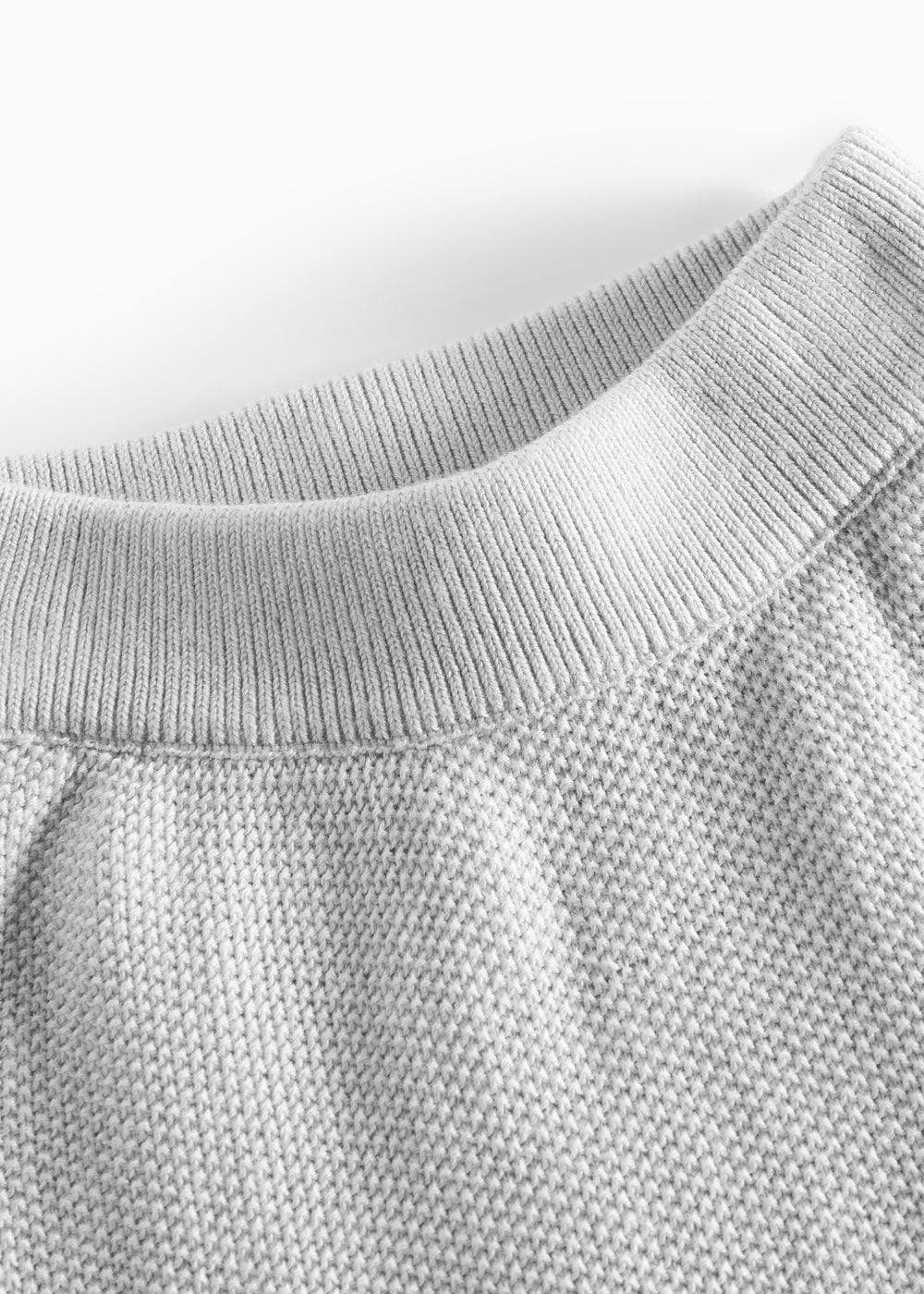 Nærbillede af halsudskæring på grå strikket babytrøje