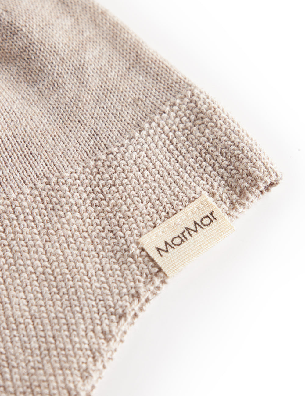 Detail of beige knitted baby hat with MarMar label