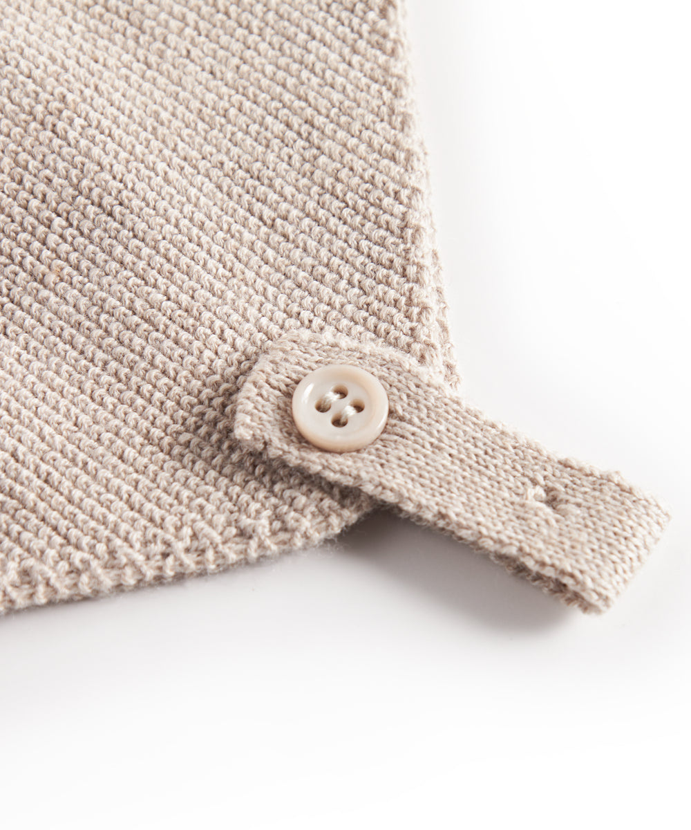 Nærbillede af knaplukning på beige strikket babyhue