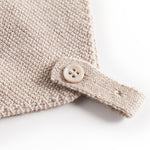 Nærbillede af knaplukning på beige strikket babyhue